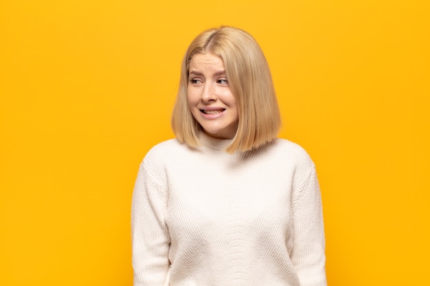 Blonde woman looking worried, stressed, anxious and scared, panicking and clenching teeth