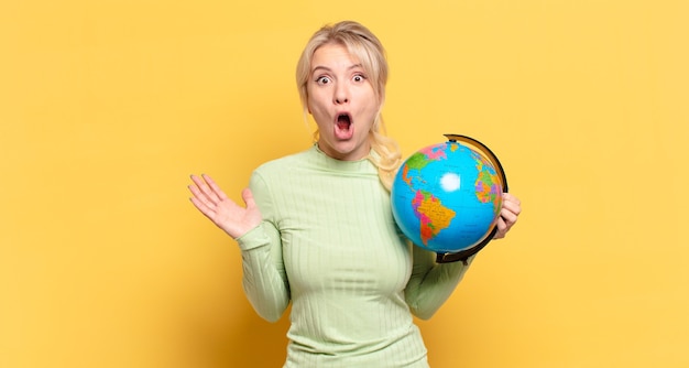 Photo blonde woman open-mouthed and amazed, shocked and astonished with an unbelievable surprise