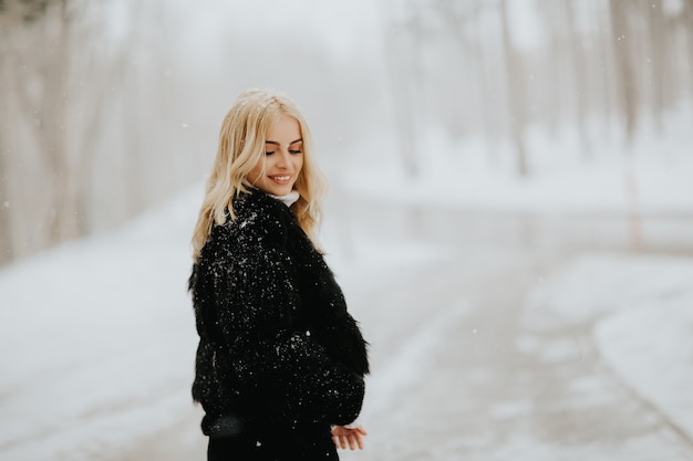 雪の冬のコートの外でブロンドの女性