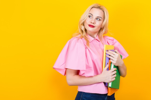 Blonde woman in pink blouse with pile of books