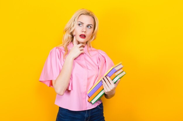 Blonde woman in pink blouse with pile of books