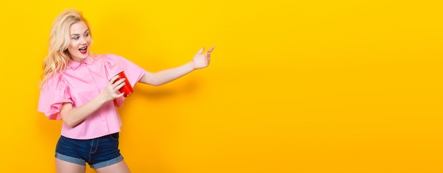 Blonde woman in pink blouse with red cup