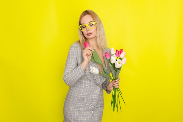 Blonde woman in plaid dress holding tulips bouquet