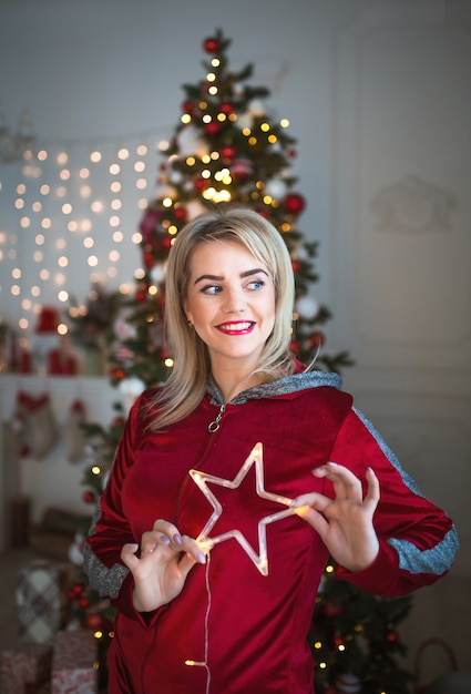 A blonde woman in a red tracksuit near a Christmas tree