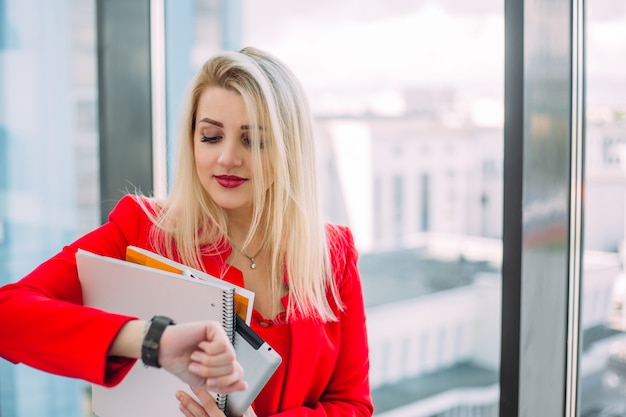 A blonde woman in red watching on her watch