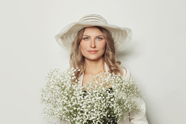 Blonde woman in romantic hat holding flowers