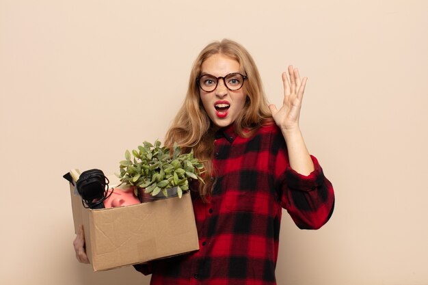 Blonde woman screaming with hands up in the air, feeling furious, frustrated, stressed and upset