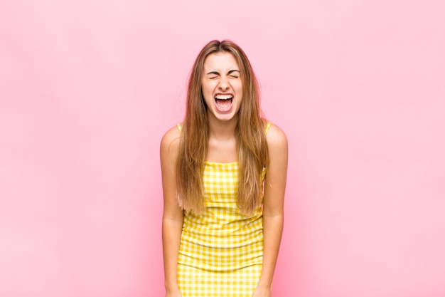 Blonde woman shouting aggressively, looking very angry, frustrated, outraged or annoyed, screaming no