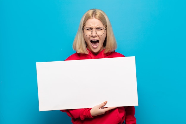 Blonde woman shouting aggressively, looking very angry, frustrated, outraged or annoyed, screaming no