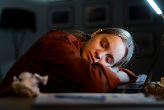 Foto donna bionda che dorme sul computer portatile