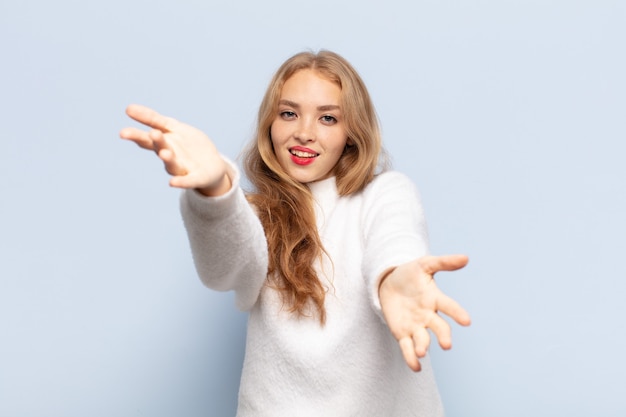 Blonde woman smiling cheerfully giving a warm, friendly, loving welcome hug, feeling happy and adorable