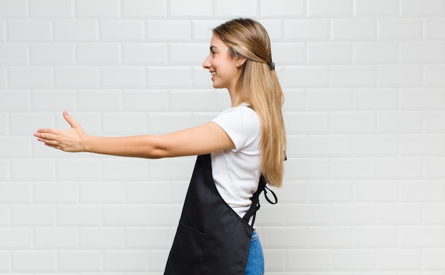 Foto donna bionda sorridente, salutandoti e offrendoti una stretta di mano per concludere un affare di successo, concetto di cooperazione