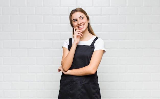 Blonde woman smiling happily and daydreaming