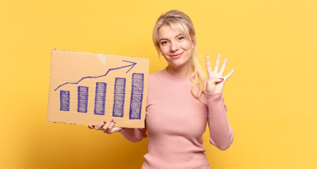 Foto donna bionda che sorride e sembra amichevole, mostrando il numero quattro o quarto con la mano in avanti, contando alla rovescia