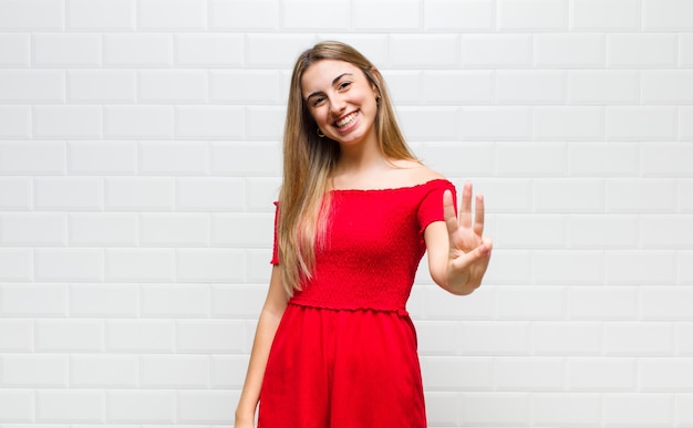 Blonde woman smiling and looking friendly, showing number three or third with hand forward, counting down