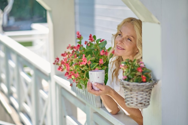 A blonde woman standing near the flowers and looking dreamy