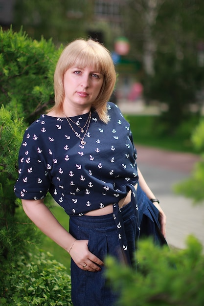 Blonde woman standing near green bush