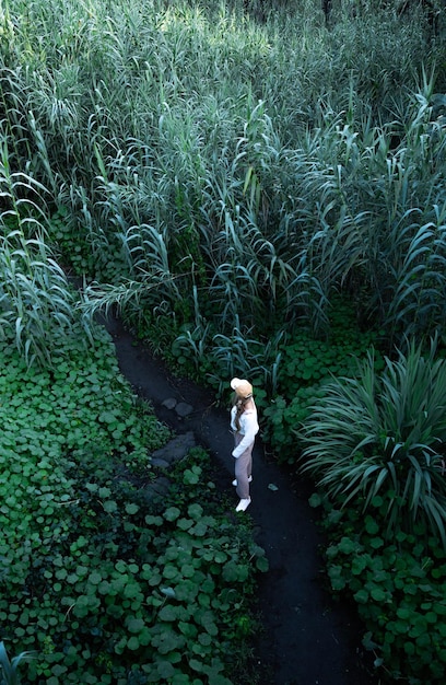 Foto donna bionda in piedi piante circondate in mezzo alla natura