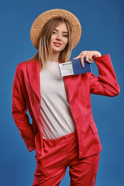 Blonde woman in straw hat holding passport and ticket. Travel concept