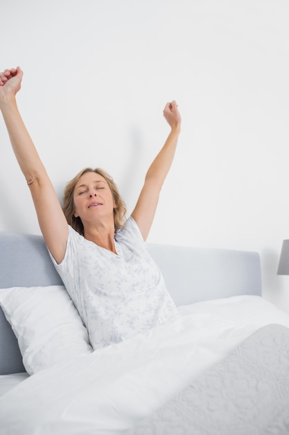 Blonde woman stretching in bed in the morning