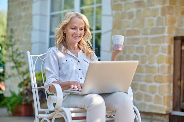 Blonde woman surfing internet while having her morning coffee