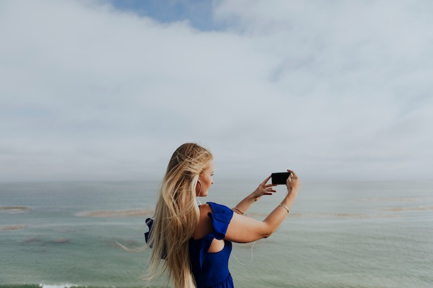金髪の女性が彼女の携帯電話で写真を撮る
