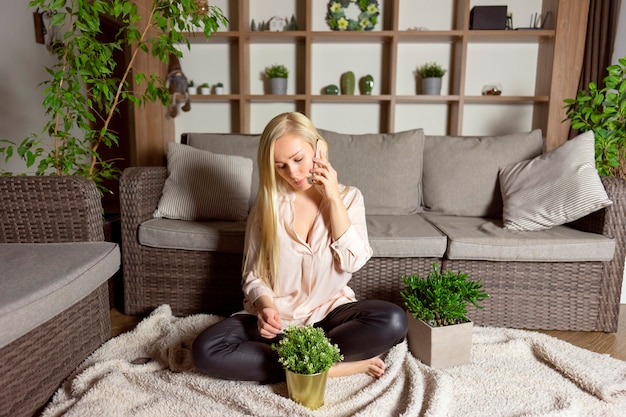 A blonde woman talking with friends by the phone at home