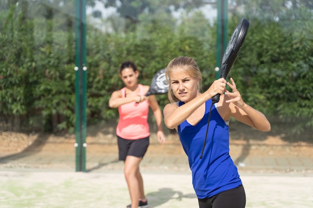 올바른 padel을 가르치는 금발의 여자는 사람들의 그룹으로 이동