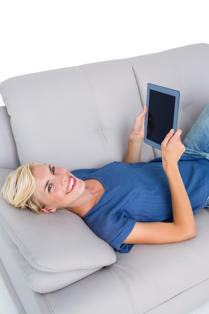 Блондинка женщина, используя ее планшет на диване