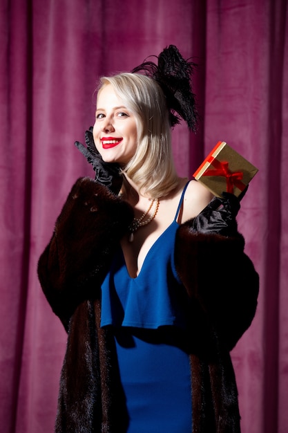 Photo blonde woman in vintage blue dress and fur coat with gift box