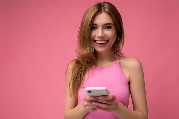 blonde woman wearing pink top poising isolated on pink background with empty space