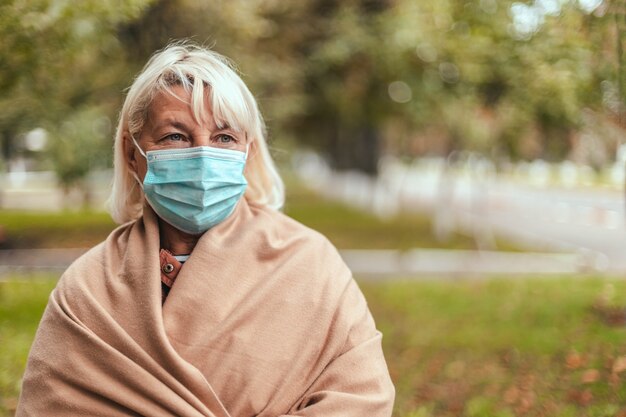 保護フェイスマスクと暖かいカシミヤスカーフを身に着けているブロンドの女性