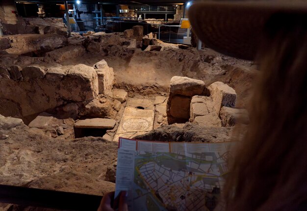 Photo blonde woman wearing a straw hat and looking at a plane in the ruins and tombs of the crypt