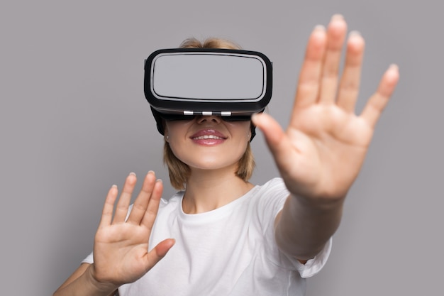 Blonde woman in white clothes is touching something while wear a vr headset