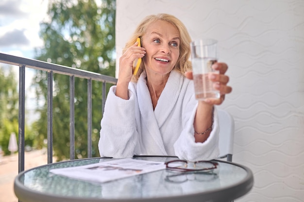 Photo a blonde woman in a white robe talking on the phone