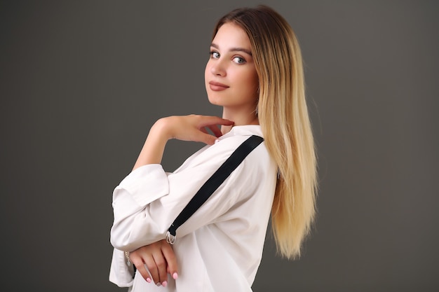 Blonde woman in a white shirt on a gray background