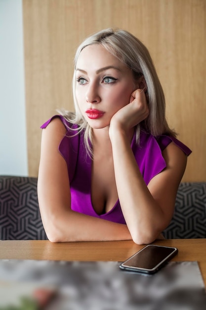 Blonde woman with cell phone in cafe