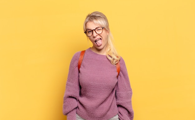 Blonde woman with cheerful, carefree, rebellious attitude, joking and sticking tongue out, having fun
