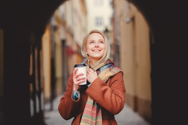 Blonde woman with cup of coffee in old town