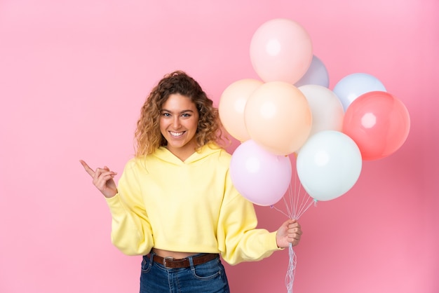 Blonde woman with curly hair holding many balloons
