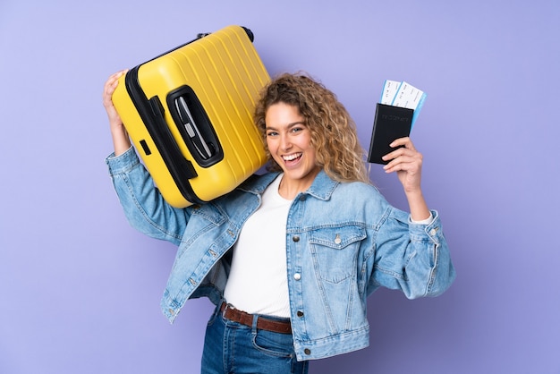 blonde woman with curly hair isolated in vacation with suitcase and passport