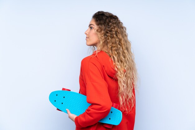 blonde woman with curly hair isolated with a skate