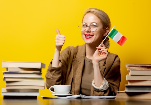 Blonde woman with flag of Italy and books on yellow