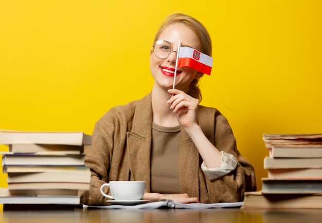 Blonde woman with flag of Poland and books on yellow