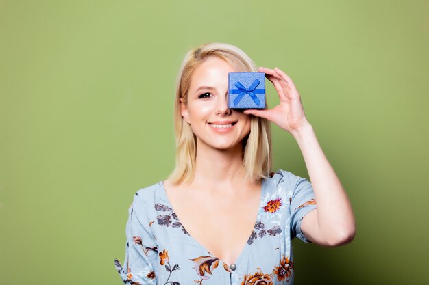 Blonde woman with gift box on green wall