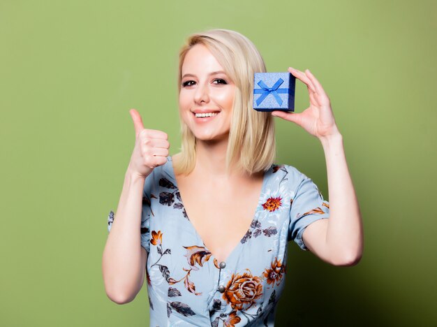 Blonde woman with gift box on green wall