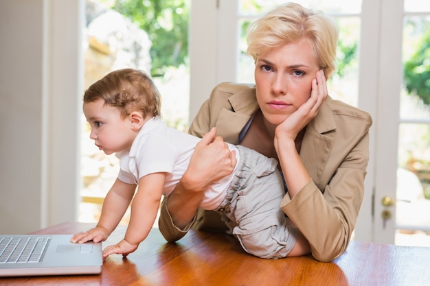 Foto donna bionda con suo figlio usando il portatile