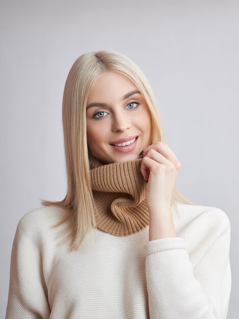 Donna bionda con i capelli lunghi in un maglione bianco