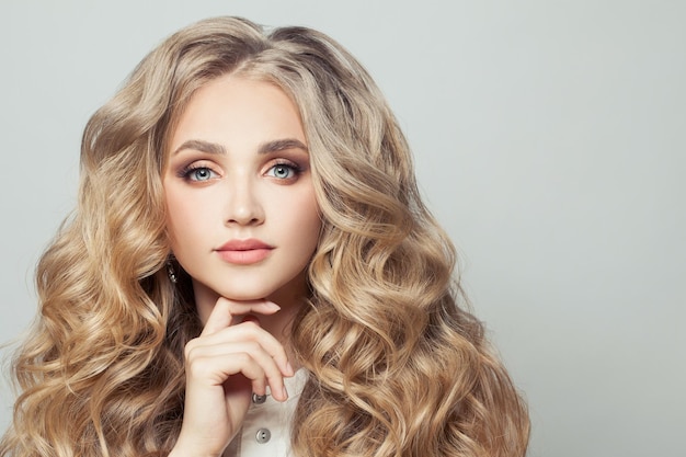 Blonde woman with long healthy curly hair on white background