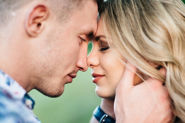 Blonde woman with loose hair in a light blue dress and a guy in the light of sunset in nature